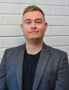 Mies seisoo tiiliseinän edessä