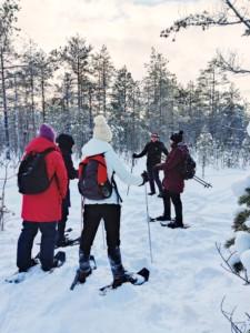 neljä naista lumikengissä suolla kuuntelee opettajaa