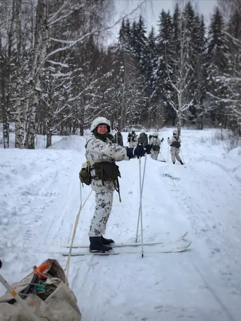Nainen hiihtää puolustusvoimien lumipuvussa MPK:n kurssilla metsässä