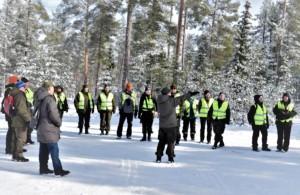 Ihmisiä seisomassa lumisella pysäköintipaikalla