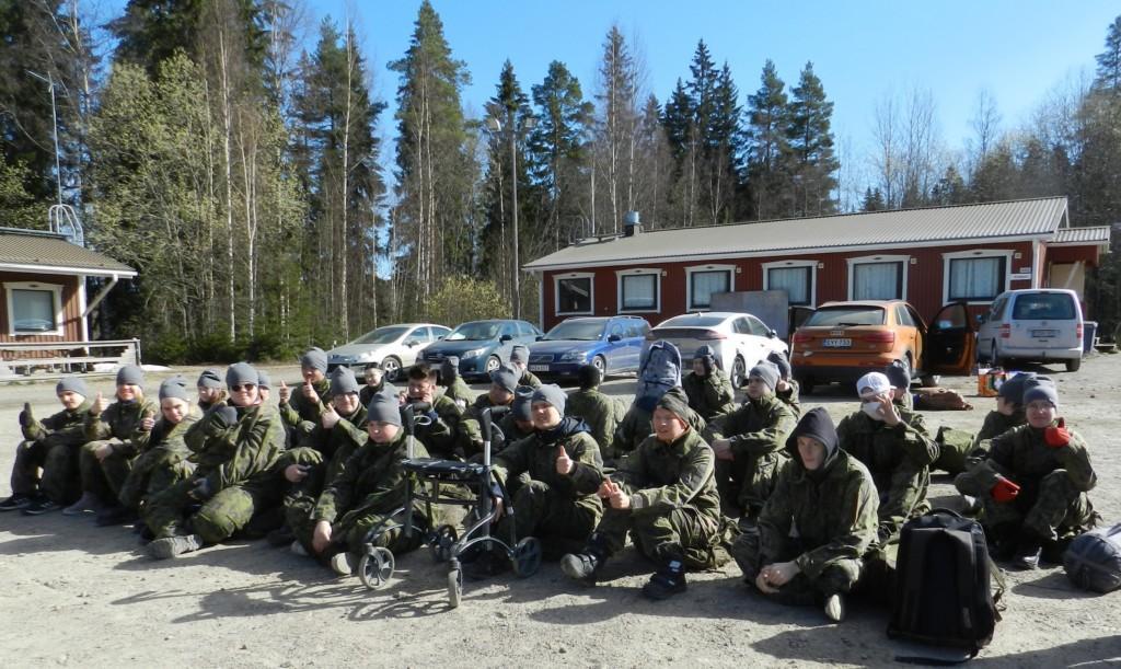 Paljon nuoria istuu maassa ja kaikilla on peukku pystyssä