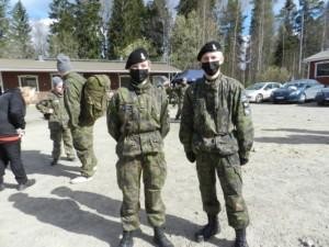 Nuori nainen ja mies maastopuvussa ja kasvomaskit kasvoilla ulkona