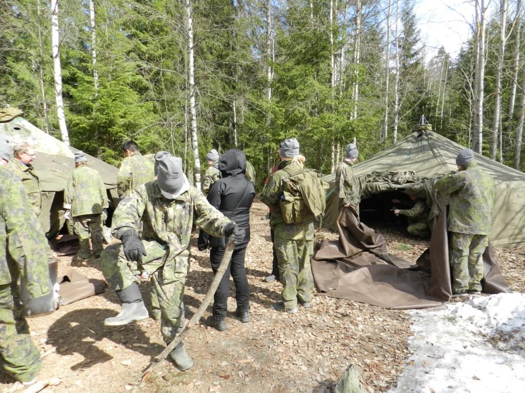 Nuoret pystyttää maastotelttaa metsässä