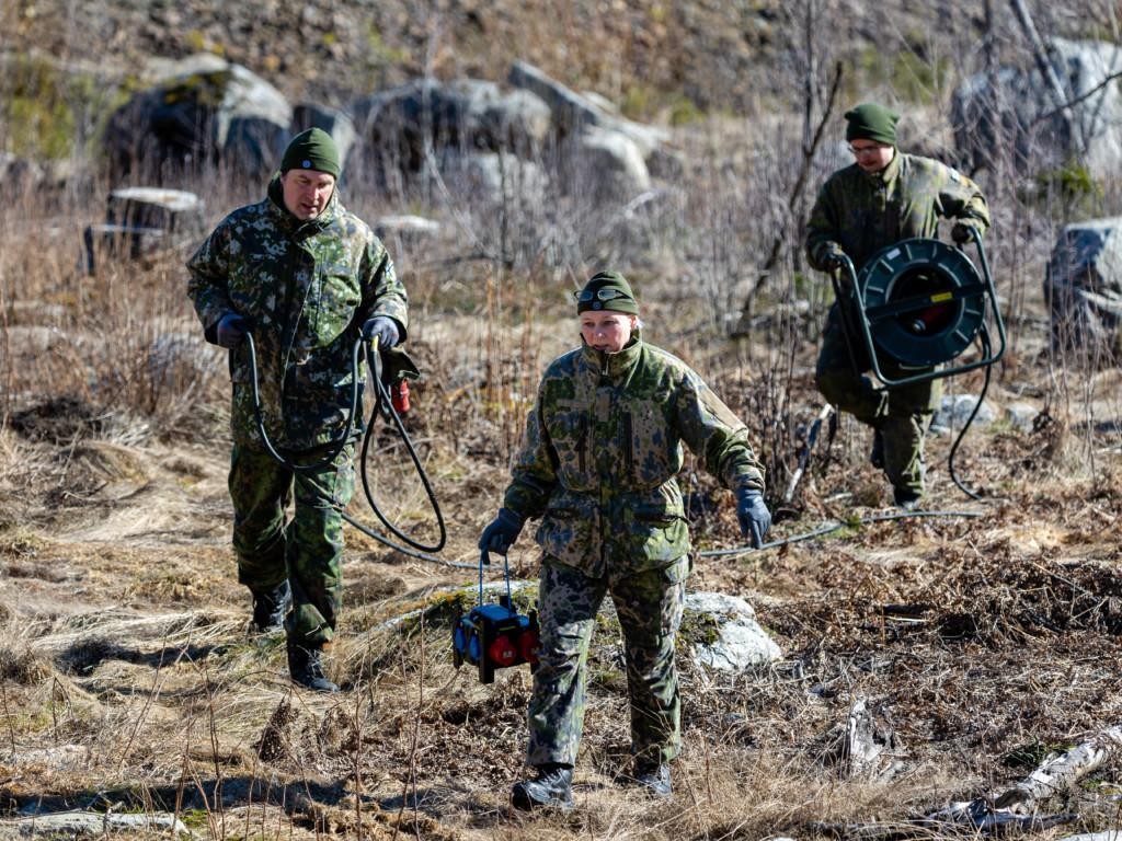 Nainen ja kaksi miestä vie virtakaapeleita ulkona