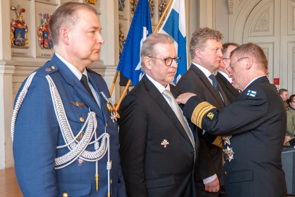 Kari Takanen kiinnittää maanpuolustusmitalia Matti Hilskalle. Kuvassa myös muut mitalin saajat.