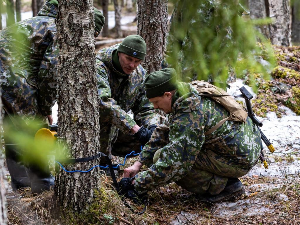 Miehet metsässä maastopuvuissa harjoittelevat kylki- ja viuhkapanosten laittoa