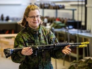 Nainen maastopuvussa ase poikittain kädessä