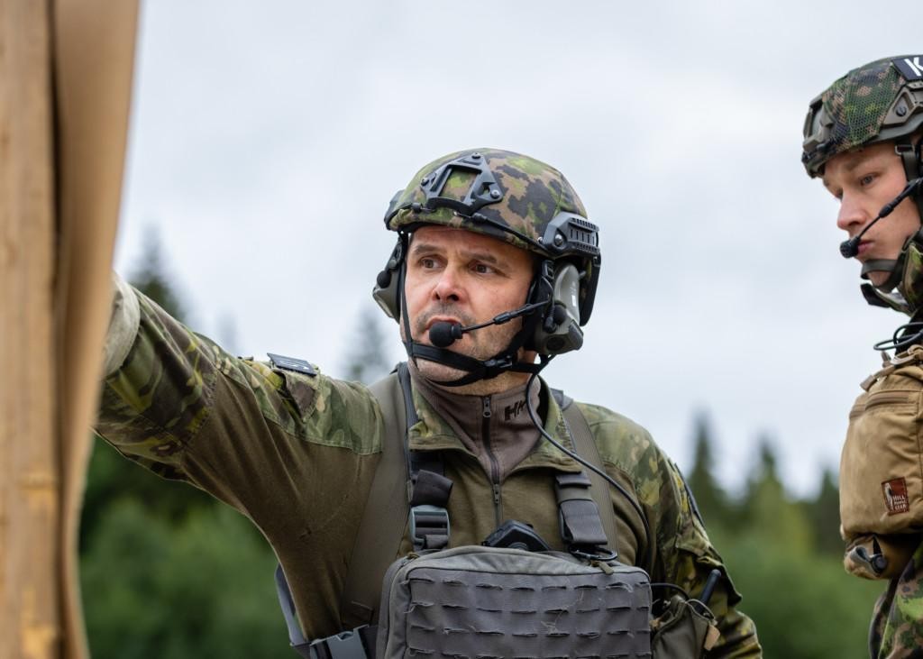 Mies maastopuvussa, kypärä päässä katsomassa ampumataulusta tarkka-ammunta tuloksiaan.