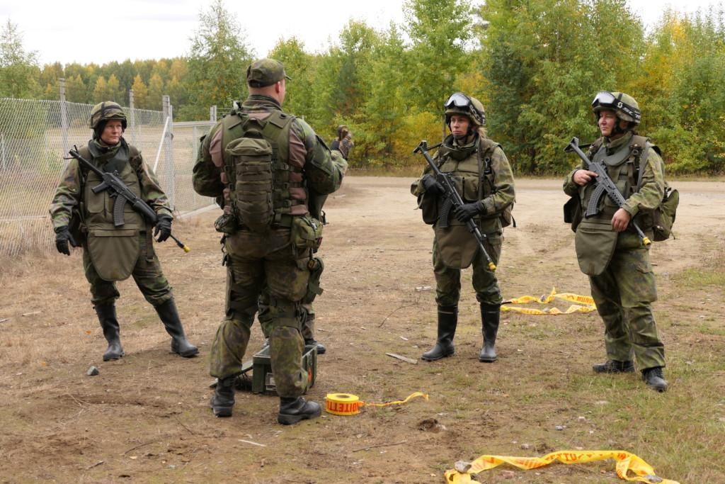 Henkilöitä maastopuvussa, jotka saavat koulutusta käsikranaatin käsittelystä