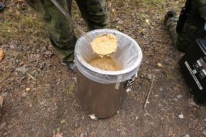 Maastoruokapönttö, josta otetaan kauhalla ruokaa