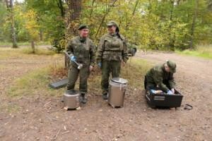 Naisia metsässä maastopuvussa kenttäruokapönttöjen äärellä
