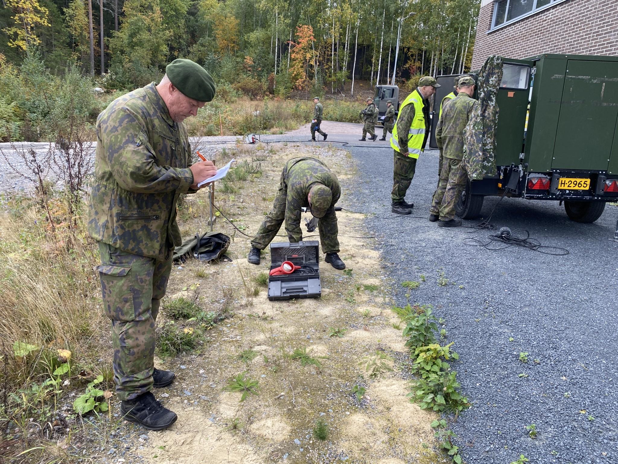 Sähkövoimakurssilaiset käyttävät peräkärryssä olevaa generaattoria. Tuomas Virtanen seuraa vieressä ja tekee muistiinpanoja.