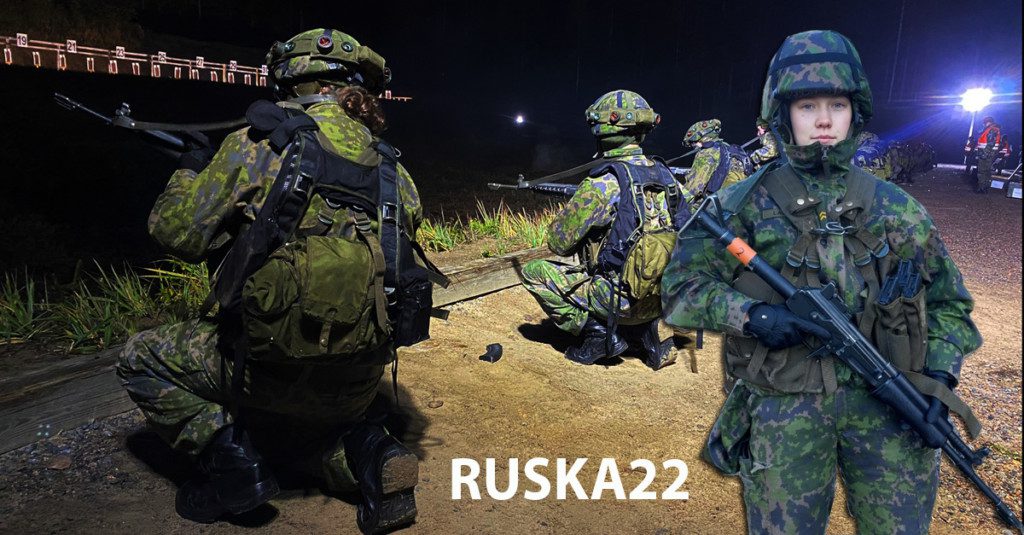 Ammuntaharjoitukset illalla. Kolme ampujaa ja nainen kivääri kädessä.