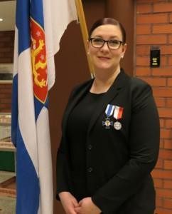Nainen tummassa puvussa mitalit rinnassa
