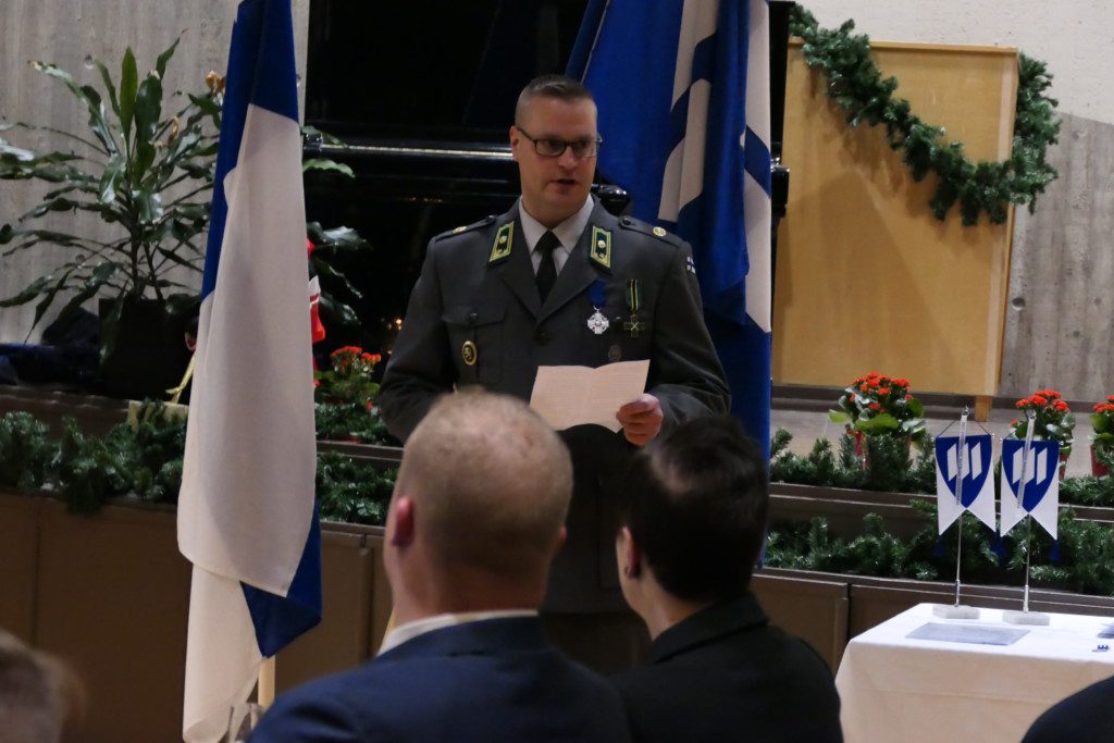 Mies sotilasasussa pitää juhlapuhetta