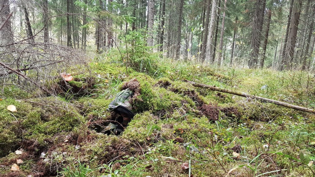 Mies piilossa maantasalla sammaleiden peitossa