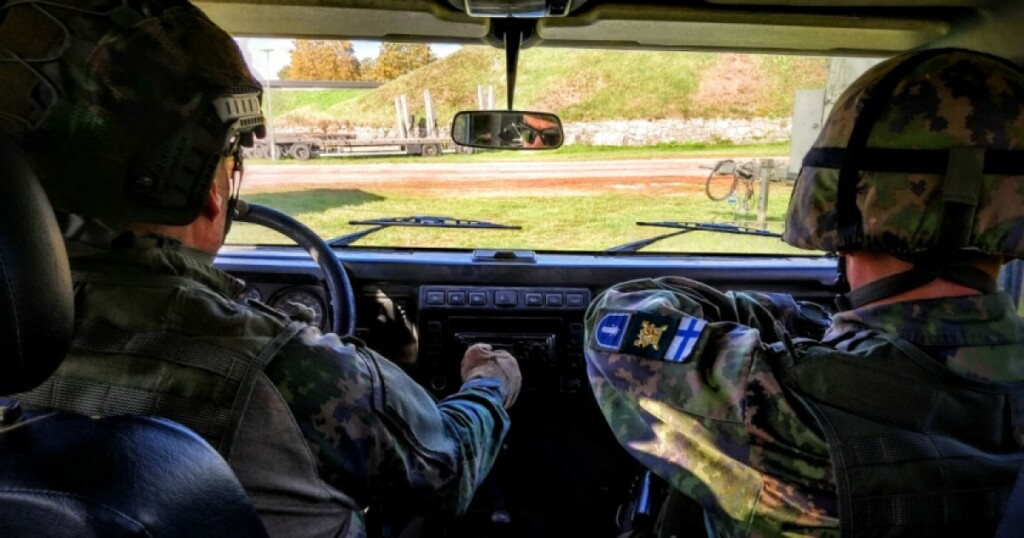 Kaksi maastoasuista ihmistä autossa