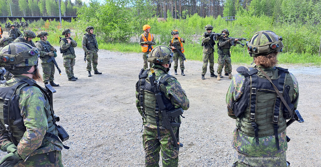 Sotilaspukuisia kouluttajia hiekkakentällä