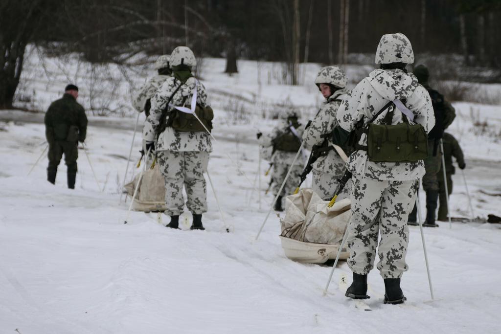 Ihmiset hiihtävät talvimaastopuvuissa ahkioiden kanssa