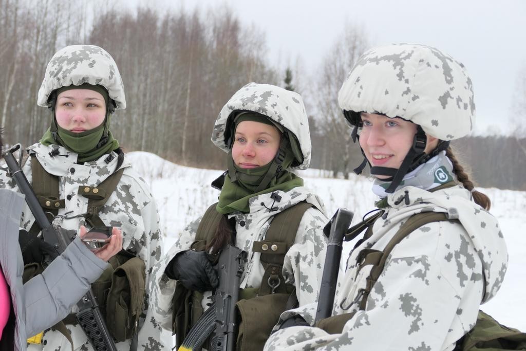 Kolme nuorta naista talvimaastopuvuissa ulkona