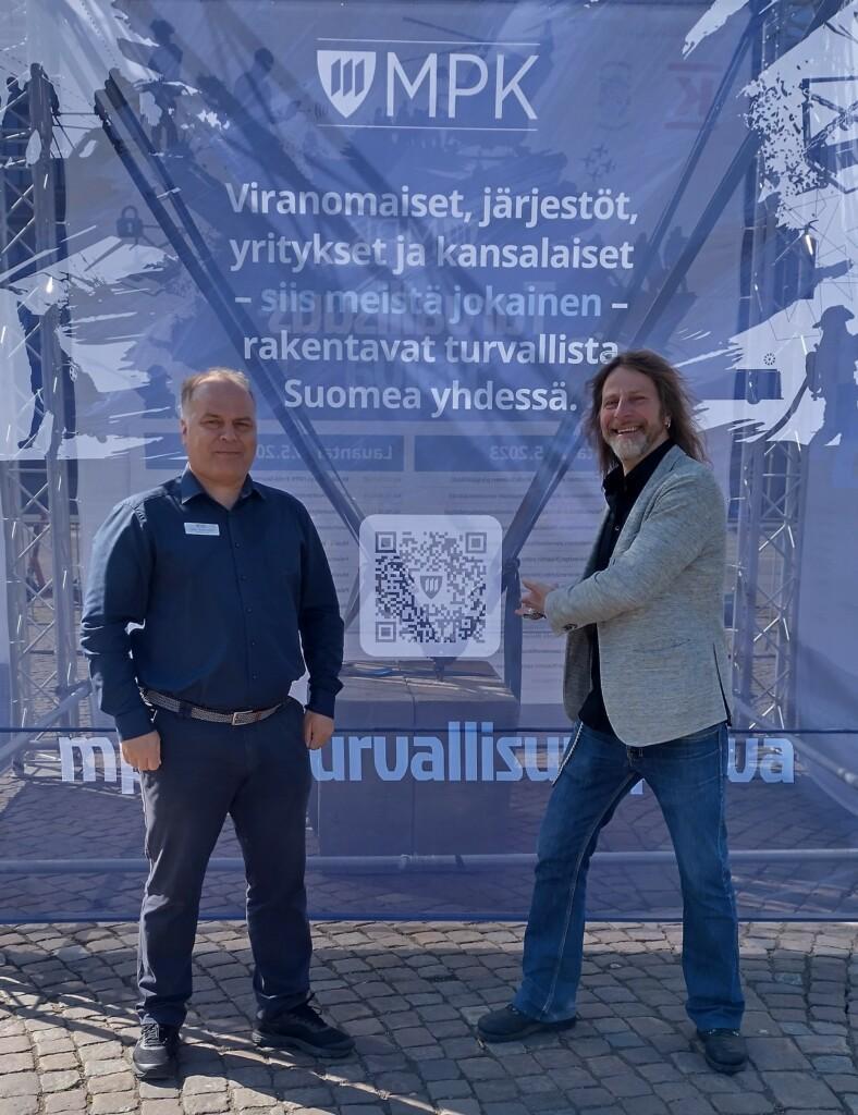 Kaksi miestä seisoo Rautatientorilla Turvallisuuspäivän trussikankaan edessä