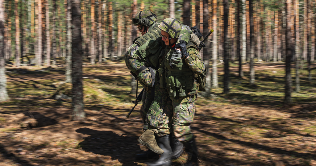 Kuvassa kaksi sotilasta kantaa kolmatta. Kyseessä evakuointi taistelutilanteessa.