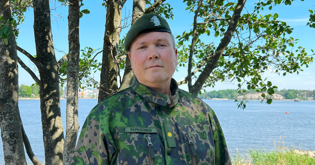 Rintakuva Juha Parkkosesta sotilaspuvussa meren rannalla