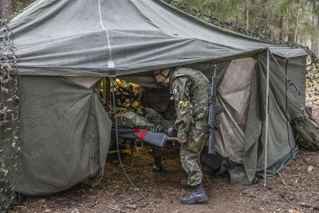 Harjoituksessa kenttälääkintätelttaan kannetaan haavoittunutta.
