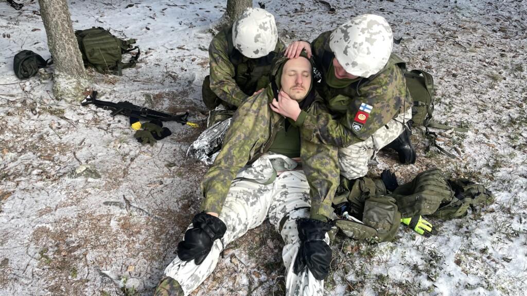 Kaksi henkilöä antaa ensiapua metsässä loukkaantuneelle.
