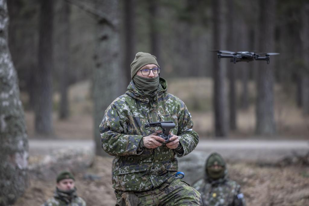Harjoituksessa sotilas lennättää dronea kahden muun sotilaan seuratessa tilannetta taustalla