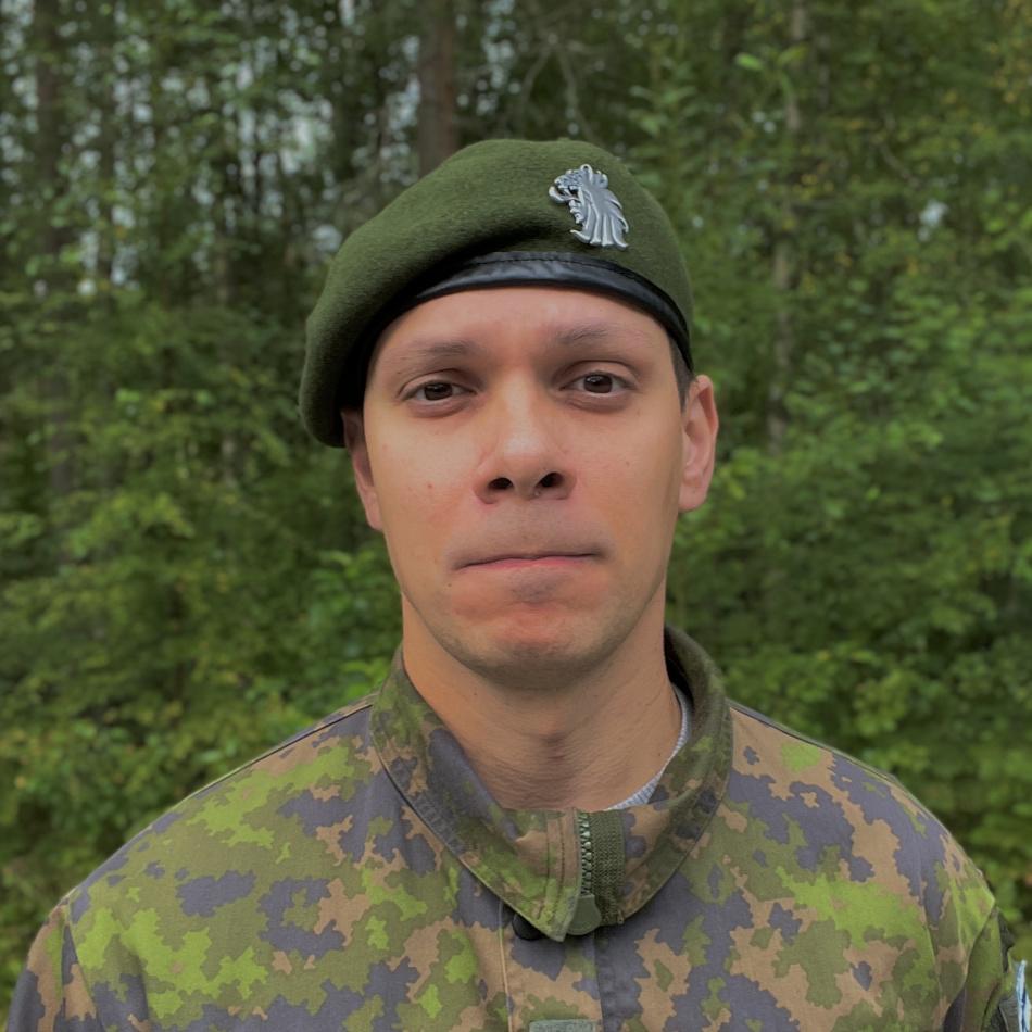 Sotilas maastopuvussa, vihreä baretti päässä.