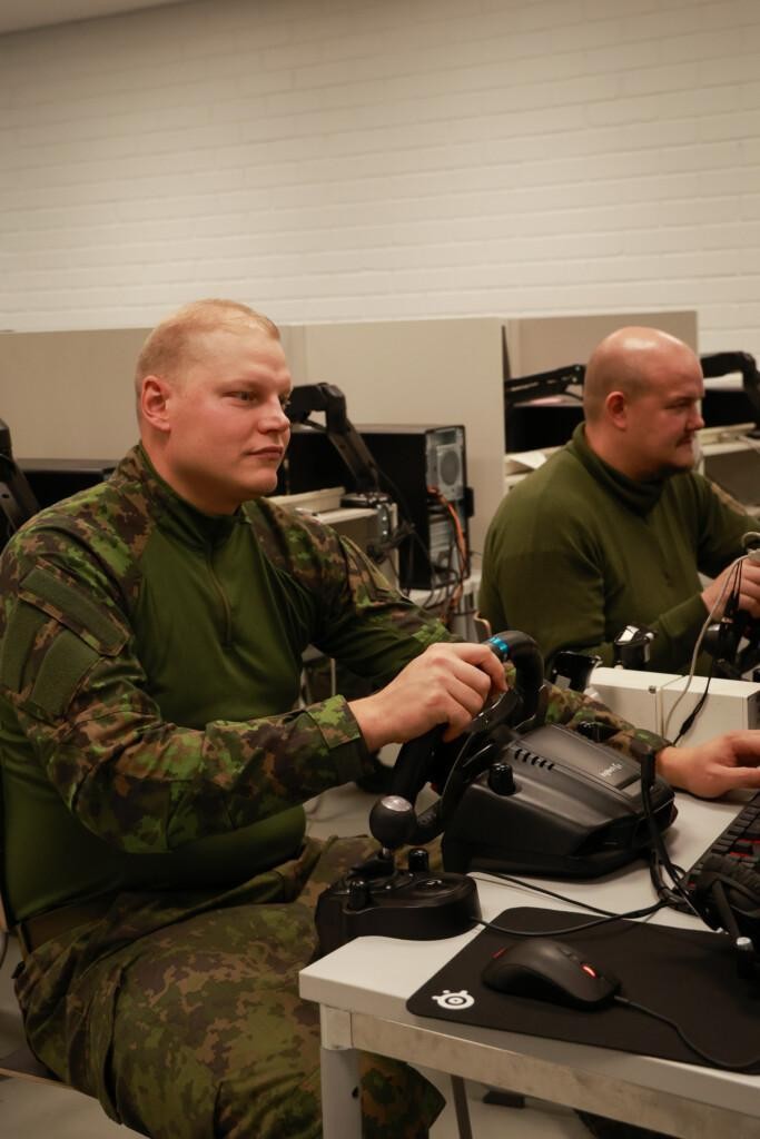 kaksi maastopukuista miestä istuvat tietokoneen ääressä.