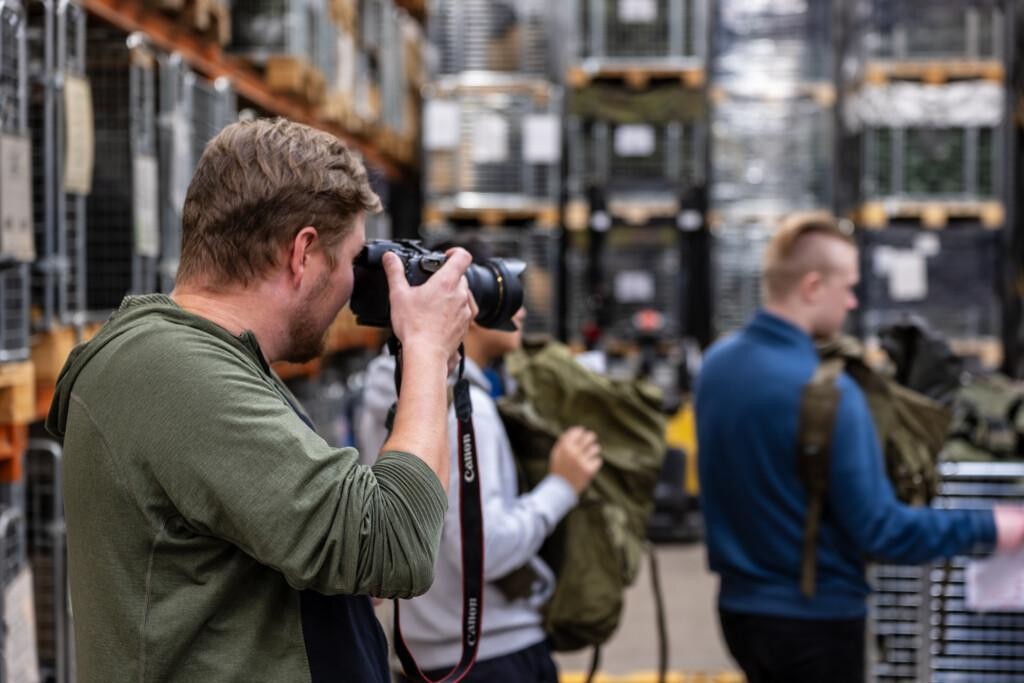 Vihreäpaitainen mies kuvaa järjestelmäkameralla.