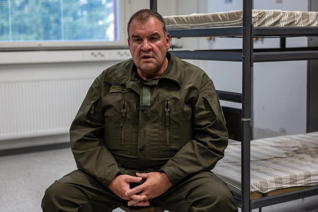 Sotilasasuinen mies katsoo keskittyneesti kameraan.