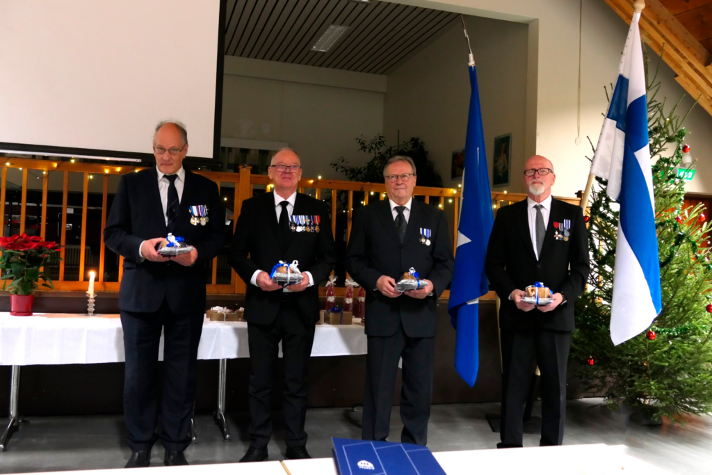 Ihmisiä juhlapuvuissa rivissä palkitsemistilaisuudessa.