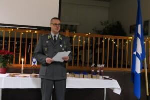 Mies sotilaspuvussa puhuu yleisön edessä