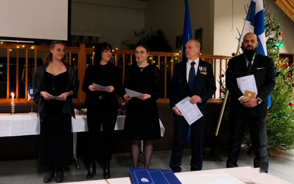 Ihmisiä juhlapuvuissa rivissä palkitsemistilaisuudessa.