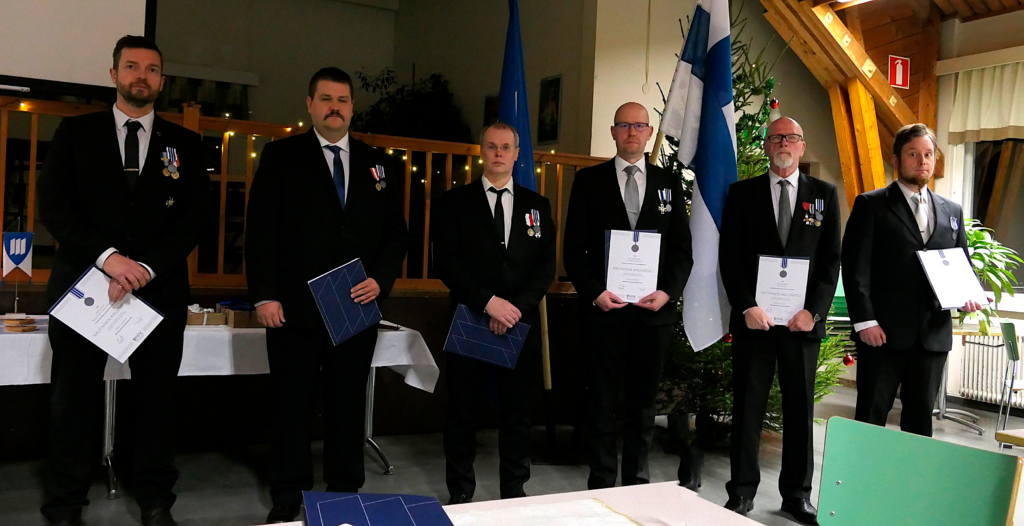 Ihmisiä juhlapuvuissa rivissä palkitsemistilaisuudessa.