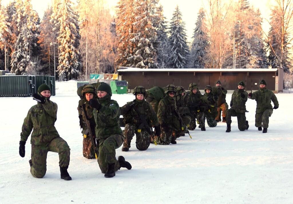 Naisia maastopuvuissa ulkona pakkasessa valmistautumassa jalkamarssiin.