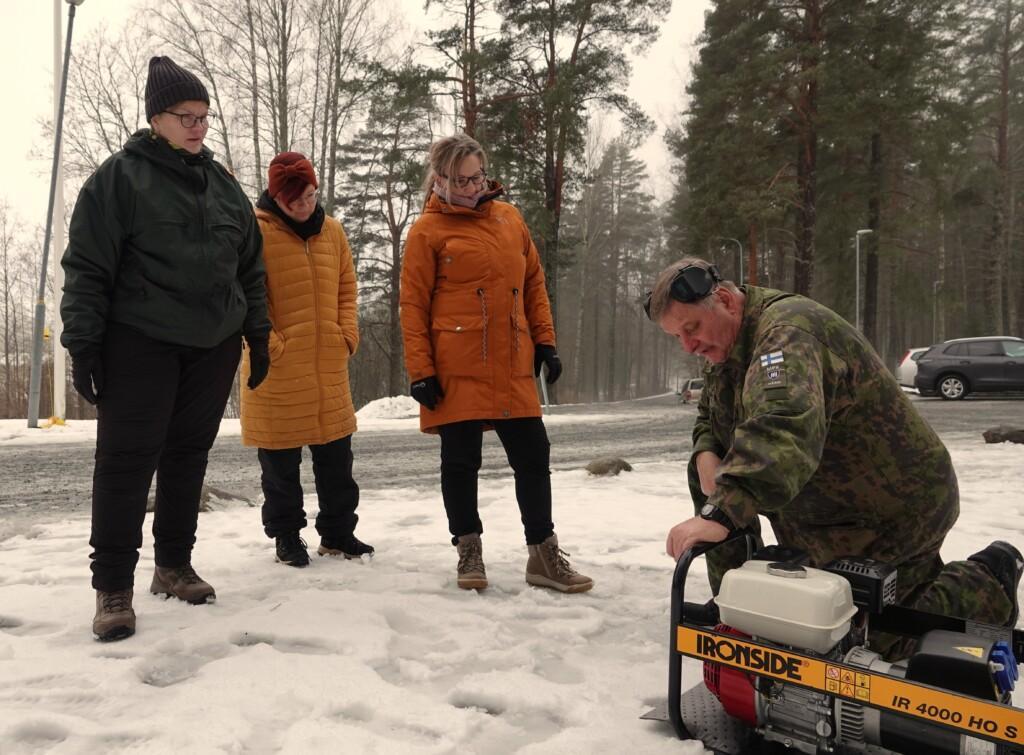 Mies opettaa naisille ulkona agrekaatin käyttöä.