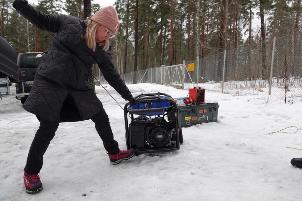 Nainen vetämässä agrekaattia käyntiin ulkona.
