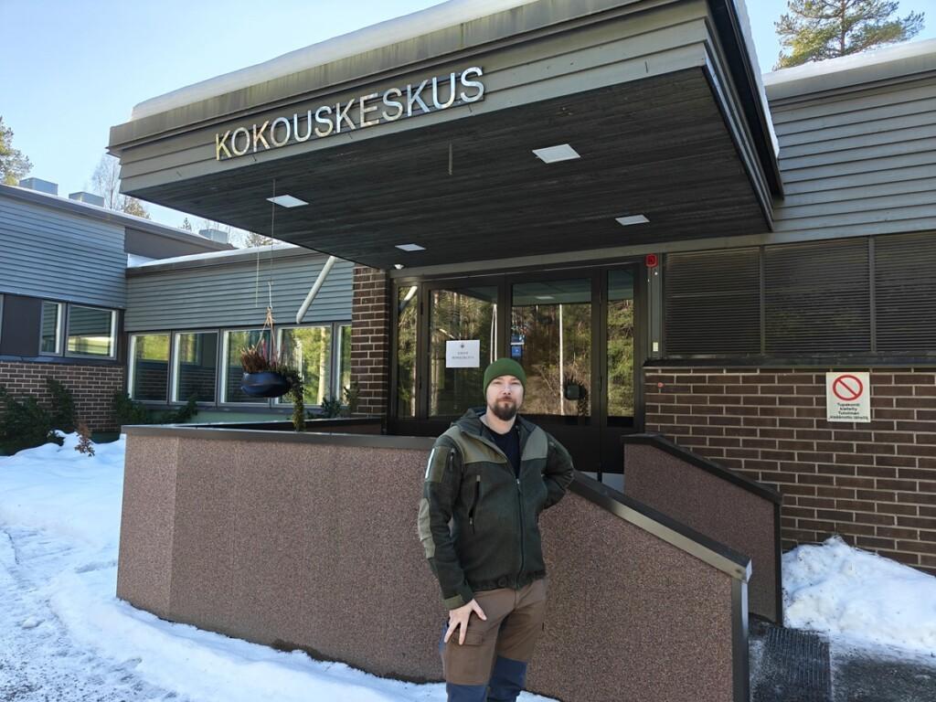 Mies seisoo ulkona rakennuksen edessä.