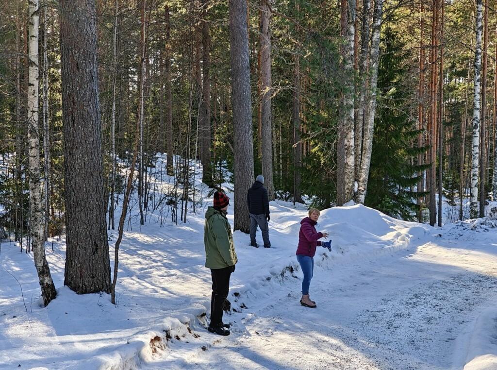 Ihmisiä lumisella metsäpolulla.