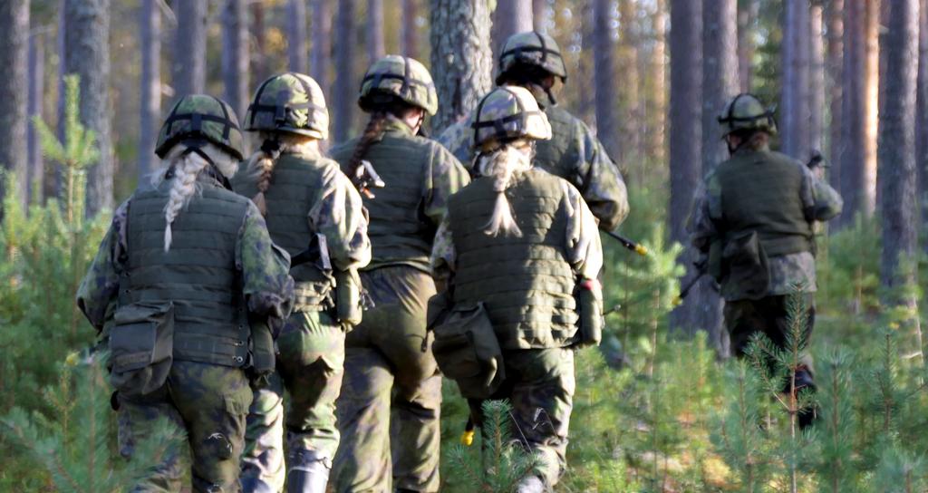 Maastopukuisia henkilöitä etenemässä metsässä